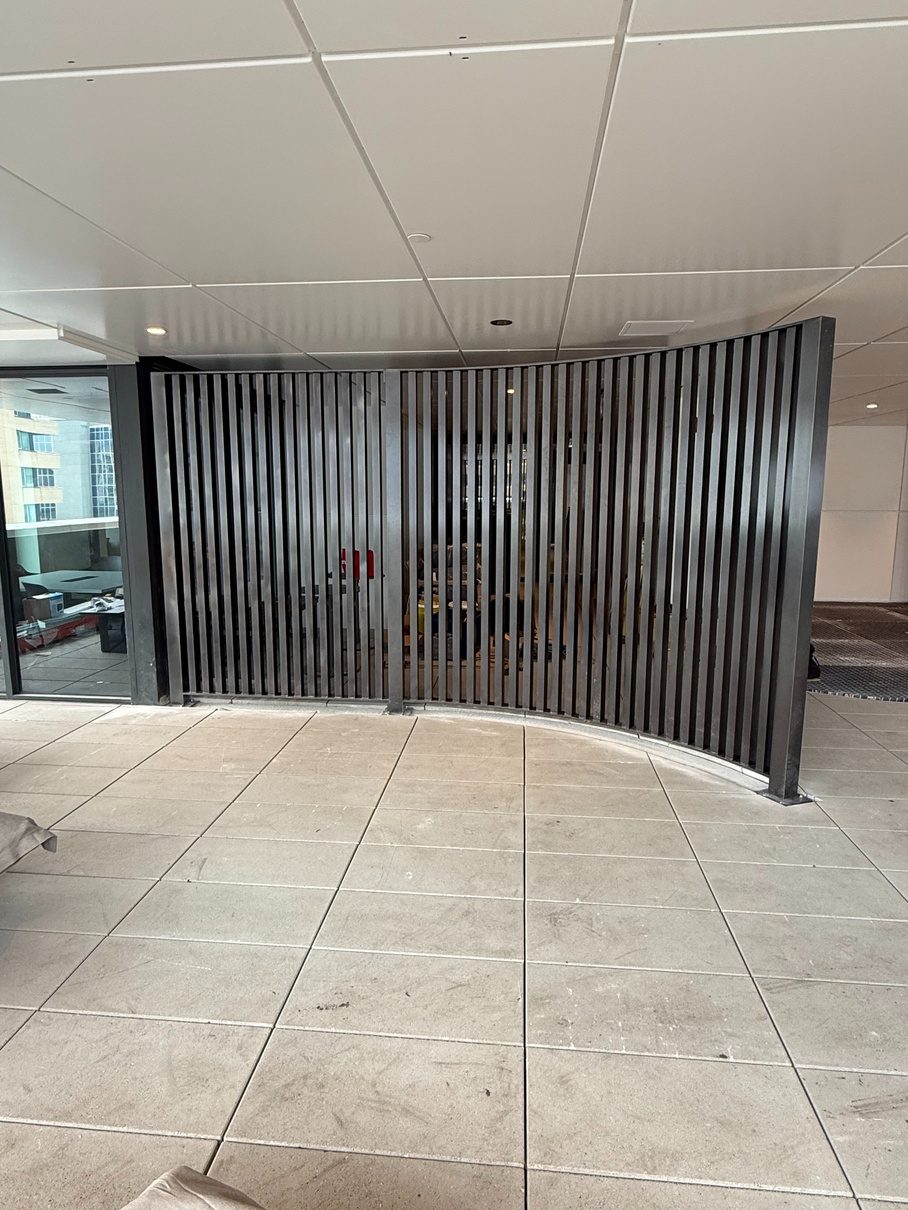 Curved slatted steel screen at a building entrance